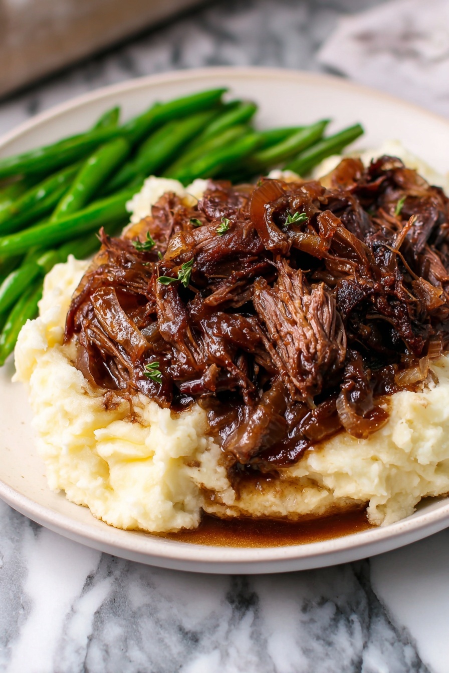 A white plate holds a three-layer dish set against a white marbled texture. The bottom layer is creamy mashed potatoes, smooth and light in color. On top is a thick layer of dark brown shredded beef with a moist texture and some visible reddish pieces and onions mixed in. To the side of the mashed potatoes and beef are fresh, bright green cooked green beans. Photo taken with an iphone --ar 2:3 --v 7