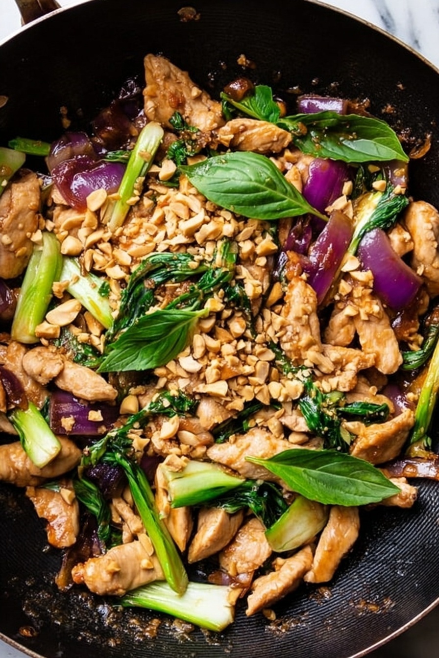 This image shows a black pan filled with a colorful stir-fry dish. The dish has about four main layers: the first layer is light brown cooked chicken strips spread evenly across the pan; the second layer has bright green pieces of bok choy with white stalks, scattered around the chicken; the third layer contains chunks of purple-red cooked onions dispersed across the mix; the fourth layer is topped with small pieces of crushed pale tan peanuts and a few fresh green basil leaves placed on top. The background is a white marbled texture. photo taken with an iphone --ar 2:3 --v 7