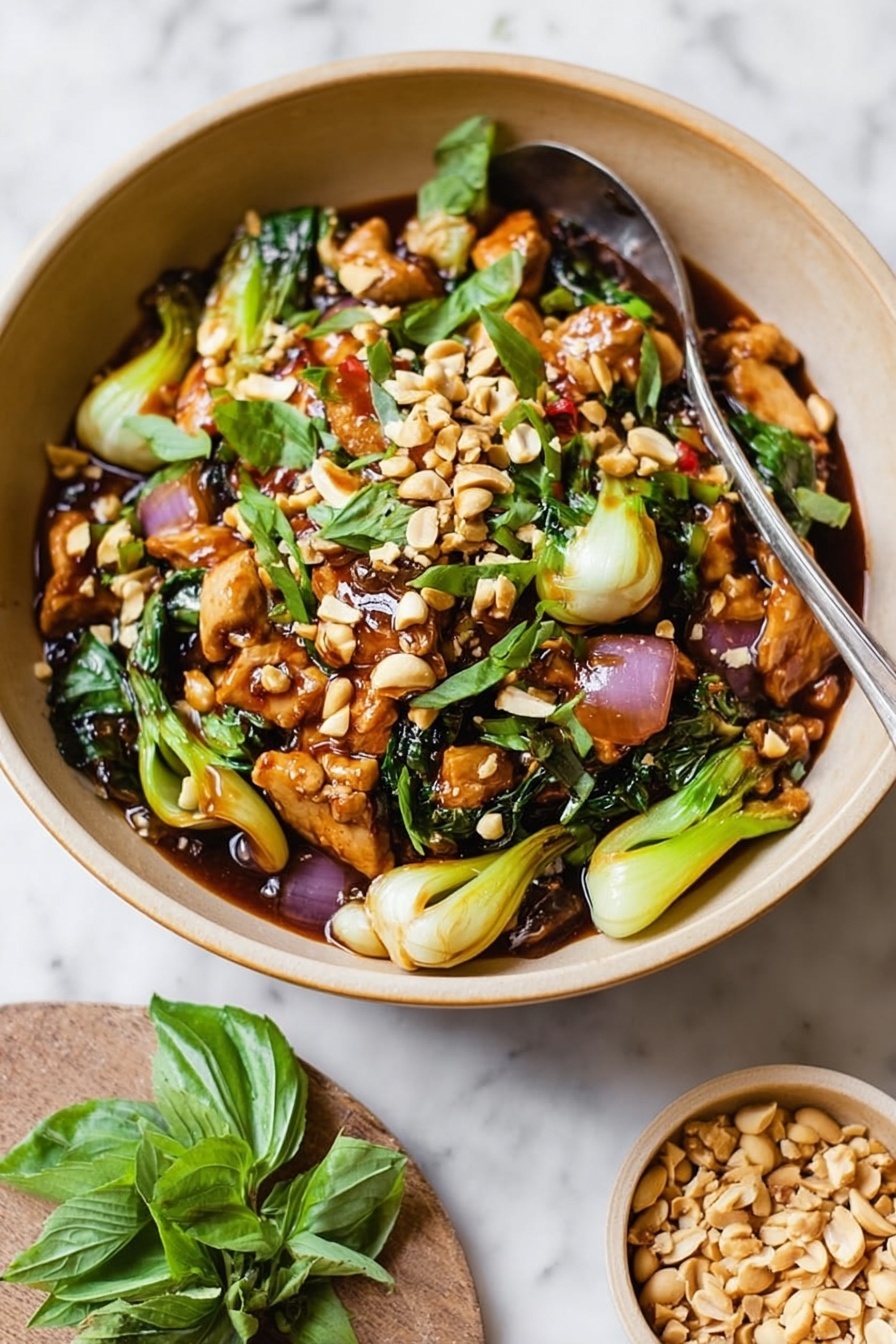 A beige bowl filled with a colorful stir-fry dish, showing three main layers: the bottom layer has pieces of light brown meat and green bok choy, mixed with some dark leafy greens; the middle layer consists of sliced red onion, light green celery, and fresh green basil leaves scattered around; the top layer is sprinkled with roughly chopped light brown peanuts. A spoon stands inside the bowl, and beside it on a white marbled surface, a small bowl of extra peanuts and green basil leaves are placed. Photo taken with an iphone --ar 2:3 --v 7