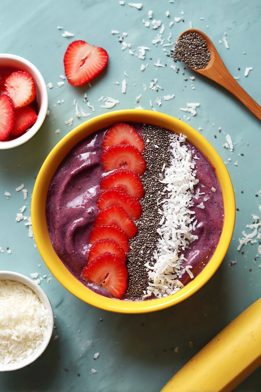 A white bowl filled with a thick, smooth, purple smoothie base. On top, there are four slices of bright red strawberries arranged in a neat row on the upper right side. Next to the strawberries, there is a crescent shape made of white shredded coconut and small black chia seeds, creating a contrasting texture and color on the creamy purple surface. The bowl is placed on a white marbled surface scattered with some coconut flakes. Near the bowl, on the right side, there is a wooden spoon with a dollop of the same purple smoothie. On the left side, there are a few strawberry slices and a small bowl of shredded coconut. At the bottom edge, a yellow banana is partially visible. Photo taken with an iphone --ar 2:3 --v 7