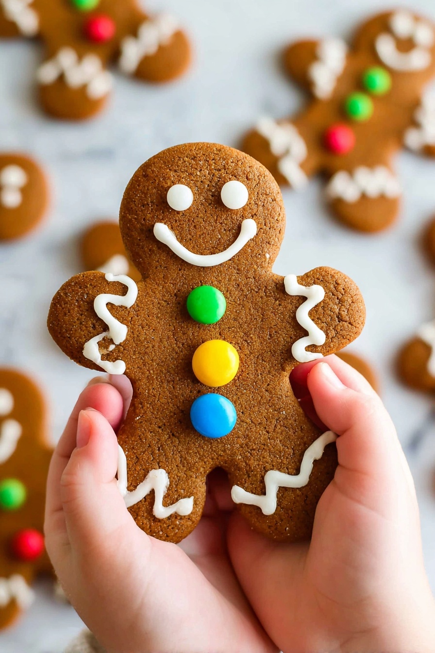 A gingerbread cookie shaped like a person is held by two small hands, with a golden-brown textured surface. The cookie has white icing eyes, mouth, and wavy lines on the arms and legs. There are three round candy buttons in blue, red, and yellow down the center of the cookie. In the background, more similarly decorated gingerbread cookies are scattered on a white marbled surface, slightly out of focus. Photo taken with an iphone --ar 2:3 --v 7