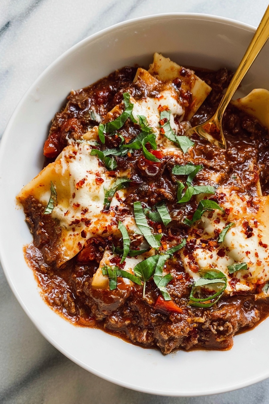 A white bowl is filled with two clear layers of food: the bottom layer is a rich, chunky red sauce with brown beans, visible pieces of tomato, and some dark greens mixed in, creating a textured and moist base. On top lie broad, flat pasta sheets partially covered by more sauce, their golden-beige color contrasting with the sauce. Dollops of soft white cheese are scattered across the pasta, topped with small green basil leaves and a sprinkle of red spice, adding spots of brightness and texture. A bronze spoon rests inside the bowl, slightly submerged in the dish. The bowl is set on a white marbled surface with loose basil leaves and a small white bowl of red spice nearby, and a wooden bowl with fresh soft white cheese slightly blurred in the background. Photo taken with an iphone --ar 2:3 --v 7