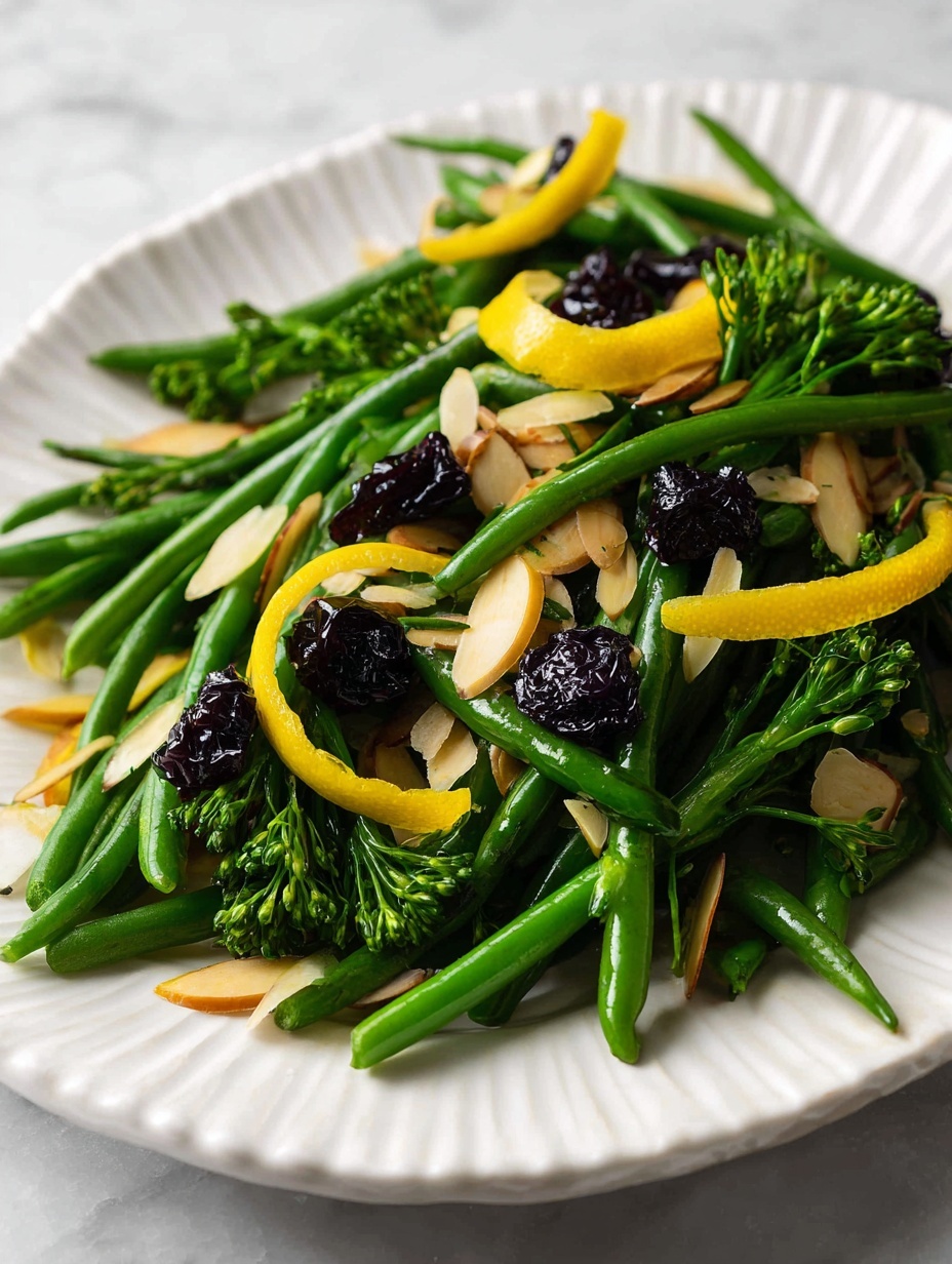 A white plate holds a fresh vegetable dish with two main layers: the bottom layer is bright green steamed broccolini with slender stalks and small florets, and the top layer consists of vibrant green steamed green beans, both arranged naturally with some overlapping. Scattered on top are thin, light brown toasted almond slices, small dark dried berries, and a few curled strips of yellow citrus peel adding a splash of color and texture. The plate is placed on a white marbled surface, with a silver fork and spoon resting on the right side of the plate. The overall look is fresh, colorful, and textured. photo taken with an iphone --ar 2:3 --v 7