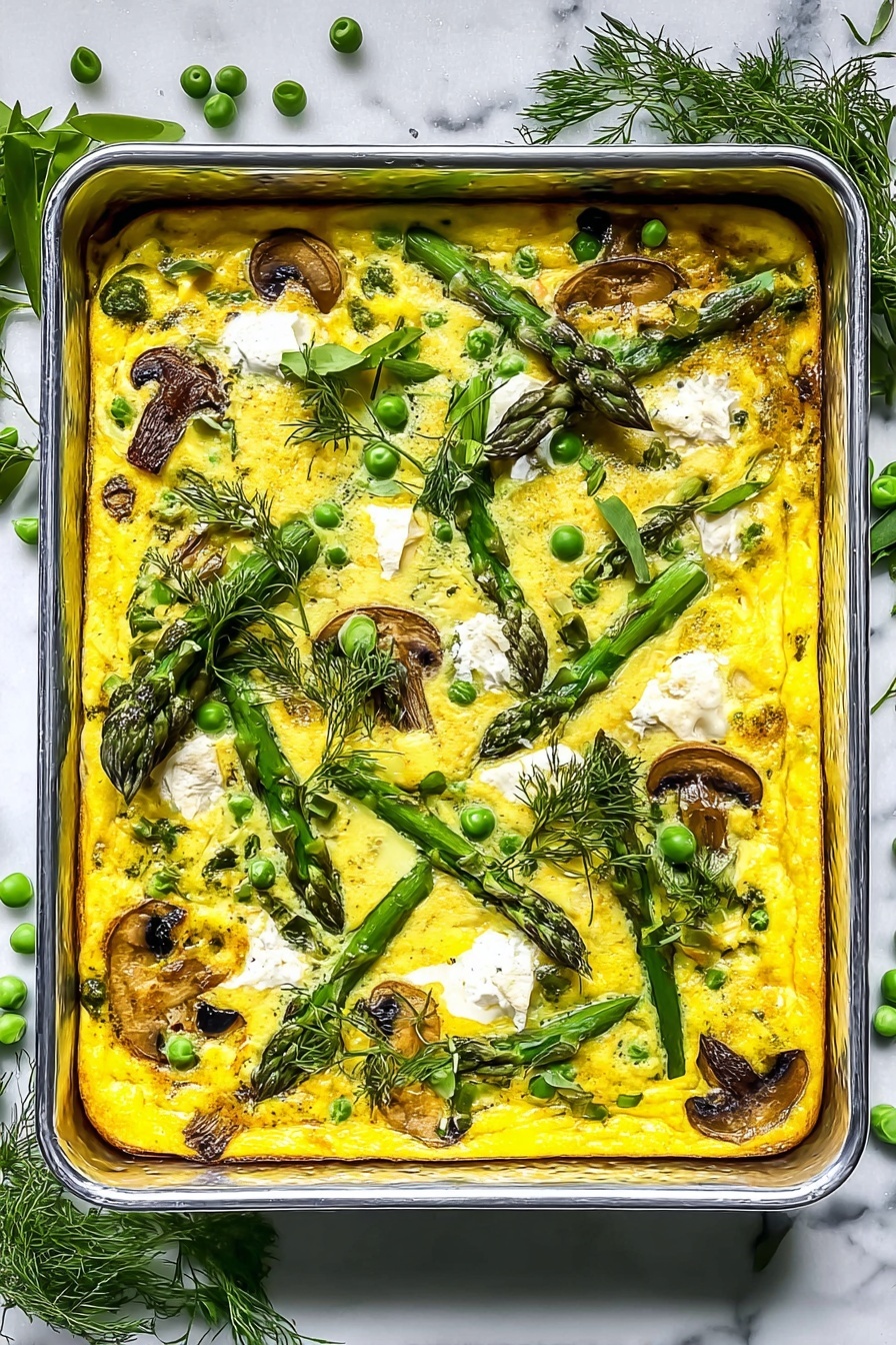 This image shows a rectangular metal baking tray filled with a yellow baked egg dish that has visible green herbs and vegetables mixed throughout. The top layer is bright yellow with scattered small white dollops of soft cheese, light brown cooked mushrooms, green peas, and green asparagus spears placed diagonally. Fresh green herbs like dill and parsley leaves are sprinkled on top and placed around the edges of the tray. The tray is set on a white marbled textured surface with some asparagus and peas scattered beside it. The lighting is bright and natural, creating fresh, vibrant colors. Photo taken with an iphone --ar 2:3 --v 7