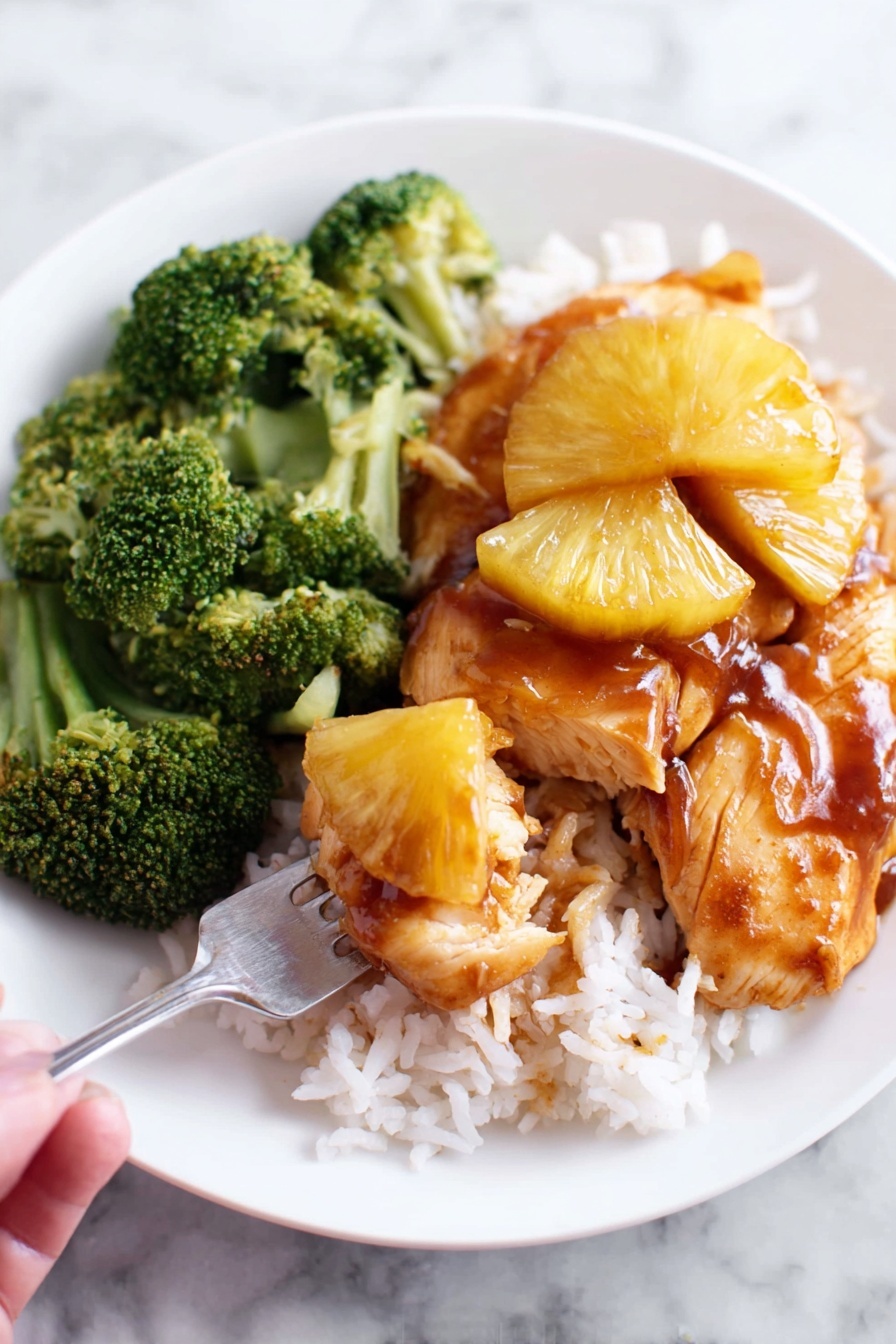 A white plate on a white marbled surface holds a meal with three main parts: a bed of white rice arranged at the bottom right, topped with two pieces of light brown cooked chicken drenched in a shiny amber glaze, and several golden yellow pineapple slices lying on top of the chicken pieces. On the top left side of the plate, a cluster of bright green broccoli adds a fresh touch. A shiny silver fork lifts a bite-sized portion consisting of rice, chicken, and pineapple toward the camera, showing the glistening texture of the sauce. photo taken with an iphone --ar 2:3 --v 7