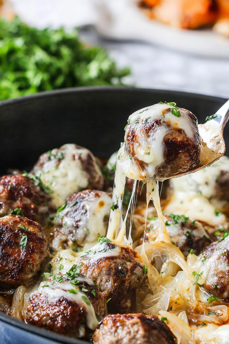 The image shows a black pan filled with brown meatballs covered in melted white cheese, which is stretchy and gooey, lifting with a silver spoon. The meatballs sit on a layer of cooked light brown onions and are sprinkled with small green parsley pieces. The background has a soft focus with green herbs on a white marbled surface, and the spoon is lifting a meatball from the pan, creating a stringy cheese effect. Photo taken with an iphone --ar 2:3 --v 7