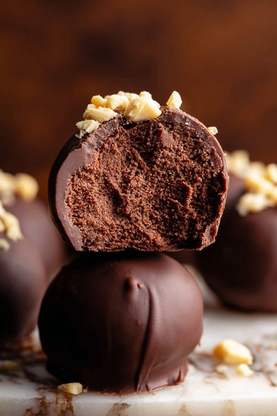 A round white bowl holds seven smooth, dark chocolate-covered balls arranged closely together. Each ball is topped with a sprinkle of small, light beige chopped nuts, creating a crunchy texture contrast. The dark chocolate coating has a glossy, even surface, and the nut pieces add a crunchy and textured layer on top. The bowl is placed on a white marbled surface, giving a clean and bright background. photo taken with an iphone --ar 2:3 --v 7