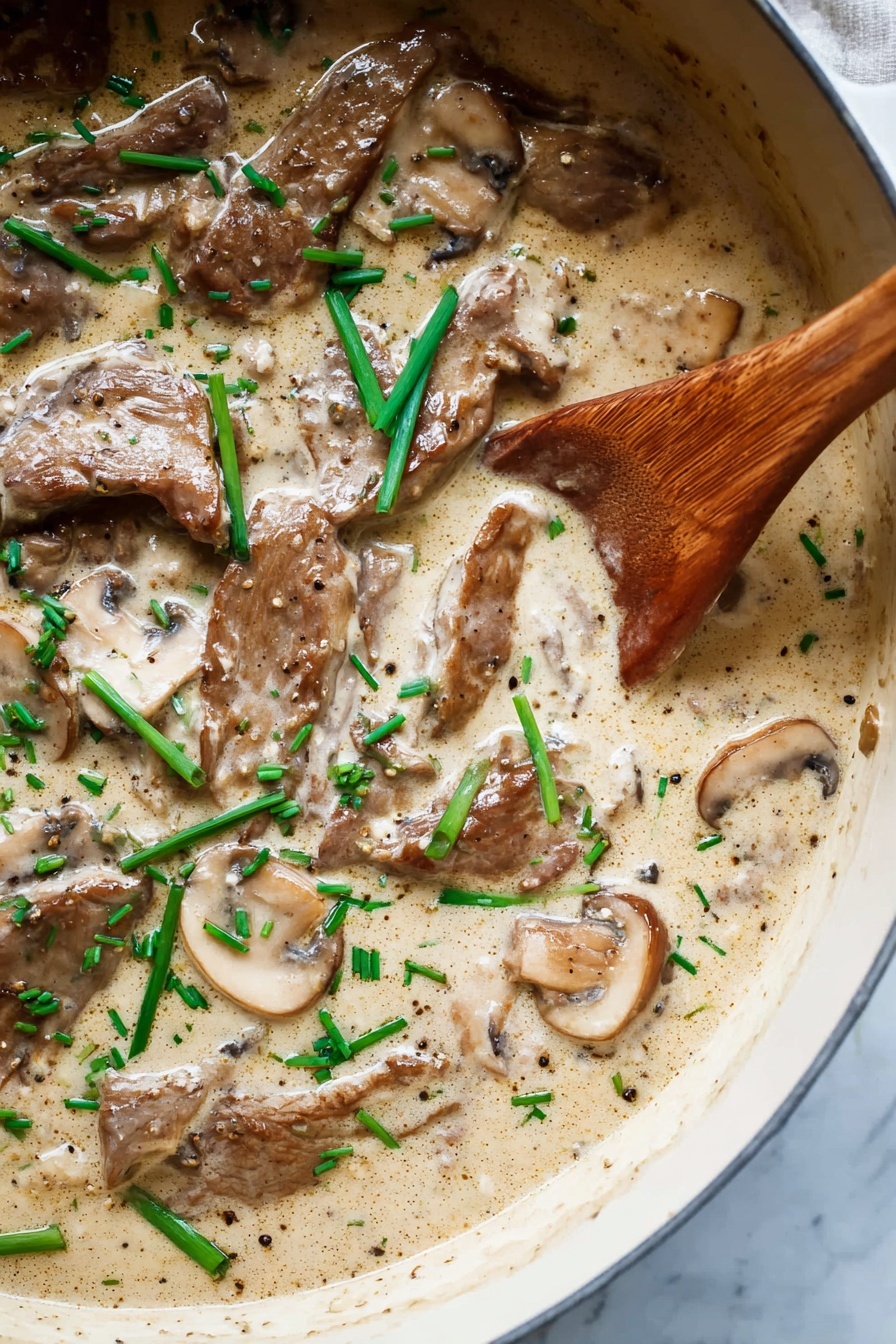 A close-up view of a creamy mushroom sauce with several slices of brown mushrooms and tender pieces of meat covered in a light tan sauce, garnished with chopped bright green herbs. A wooden spoon is partially submerged on the right side, scooping some of the sauce. The texture of the sauce is smooth and thick, filling the whole visible area of a dark pan, resting on a white marbled surface. Photo taken with an iphone --ar 2:3 --v 7